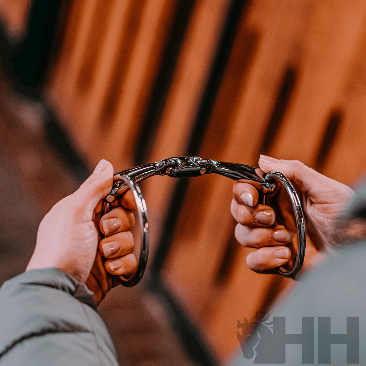 Pessoa segurando estribo metálico prateado com detalhes pretos