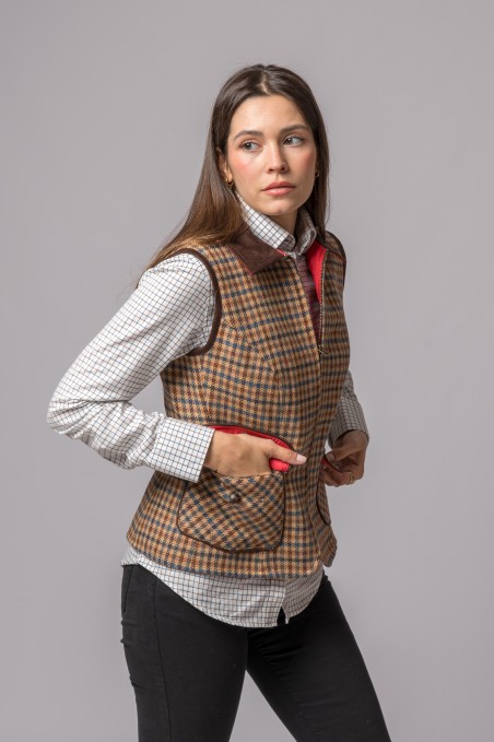 Colete feminino xadrez castanho com gola escura sobre camisa quadriculada branca e calças pretas