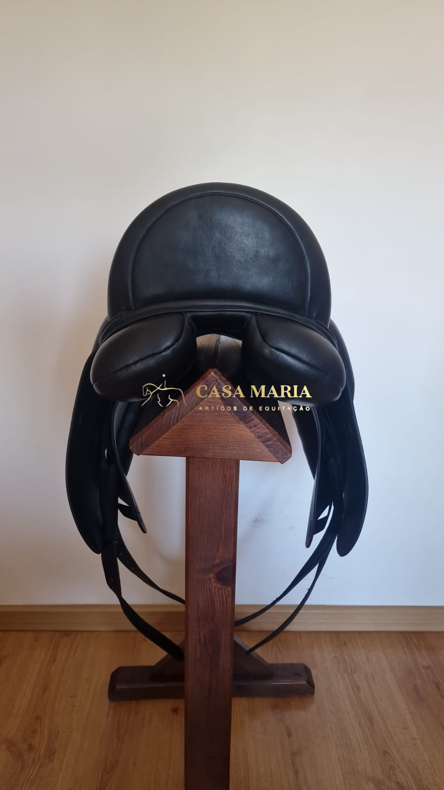 Sela de equitação preta em couro sobre suporte de madeira
