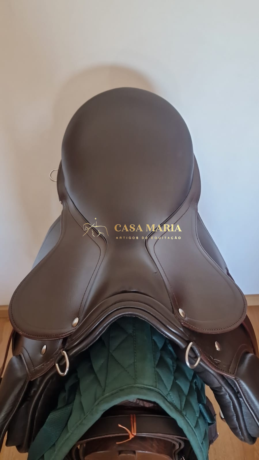 Sela de equitação castanha em pele sobre manta verde escura