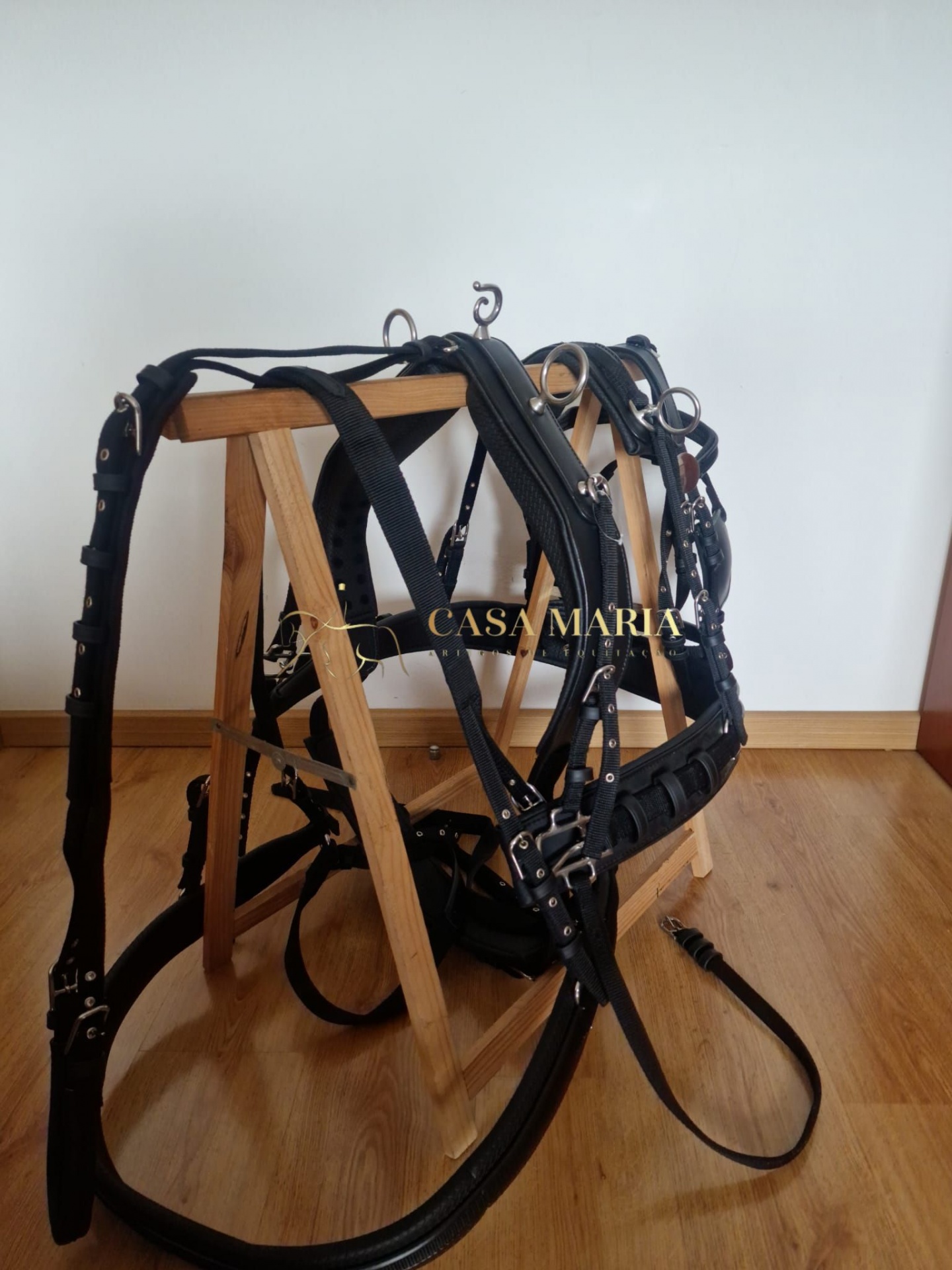 Equipamento e arreios em couro preto pendurados em estrutura de madeira