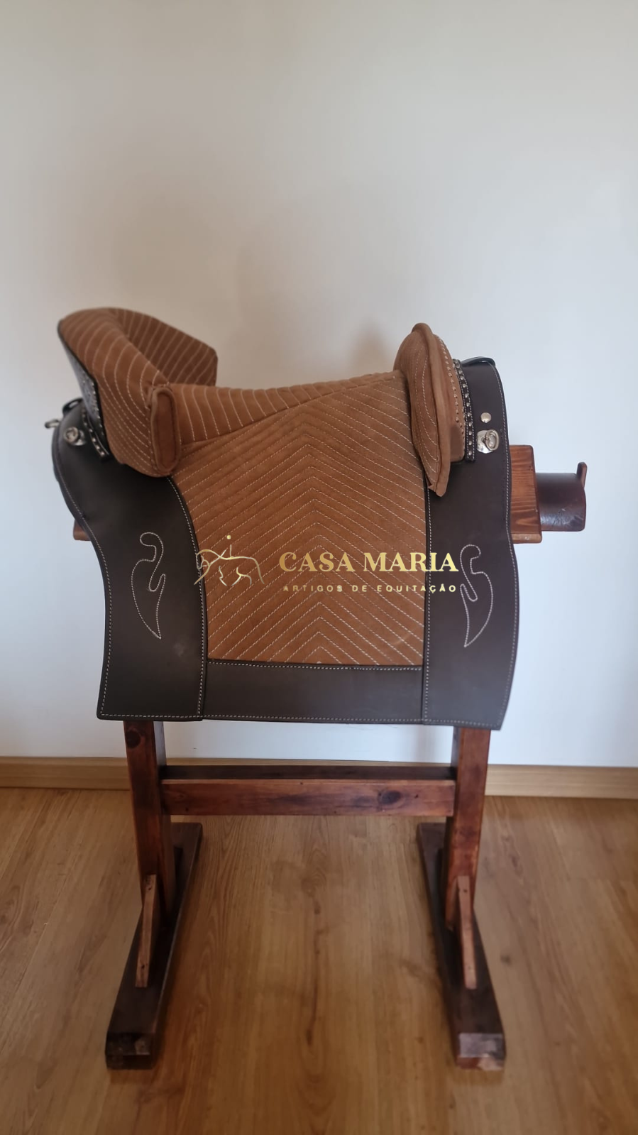 Sela de montaria castanha e bege em suporte de madeira