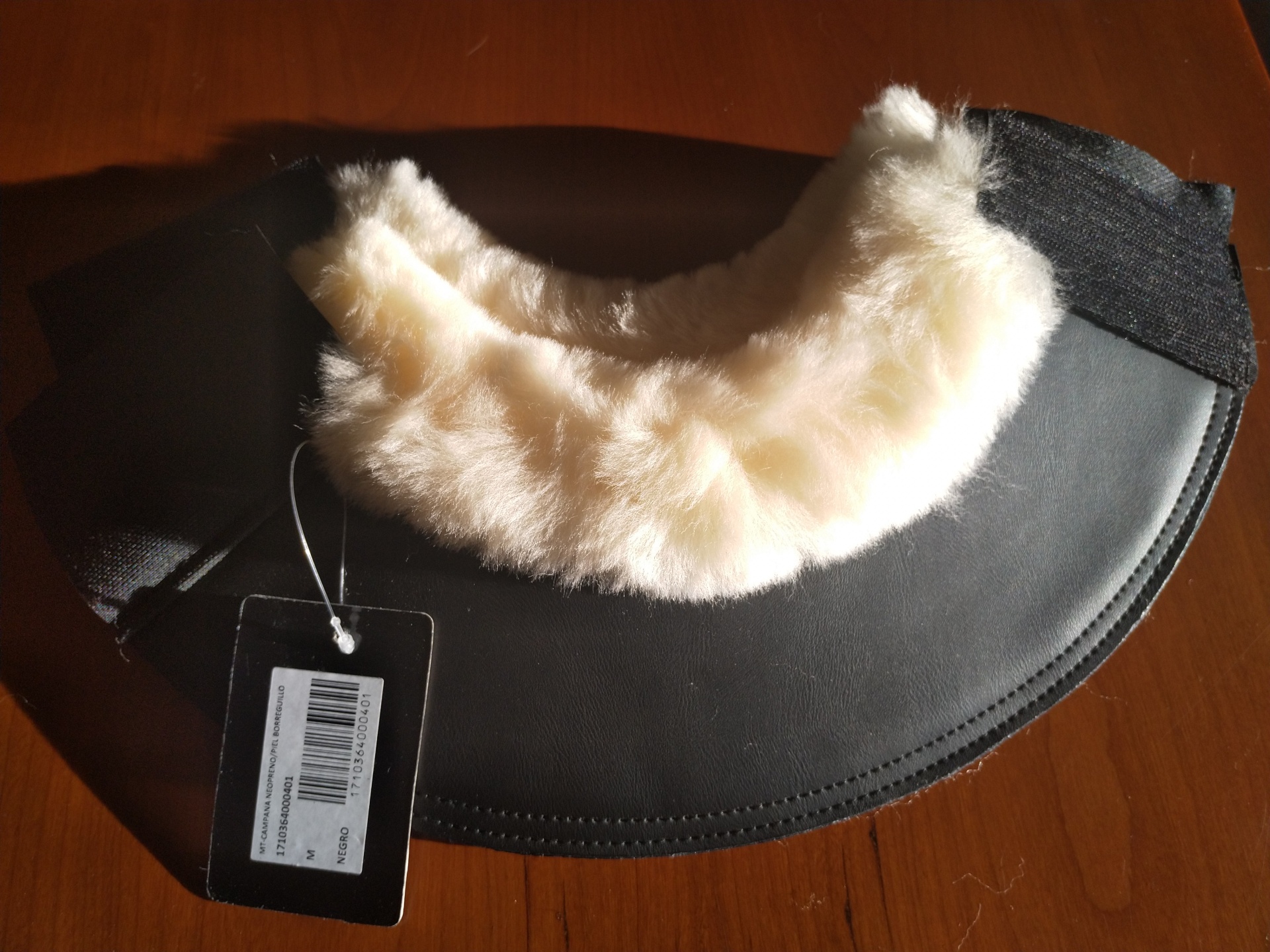 Colar de proteção do pescoço com pelo branco e base preta sobre mesa de madeira