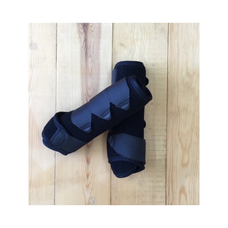 Par de protetores pretos para membros sobre piso de madeira.