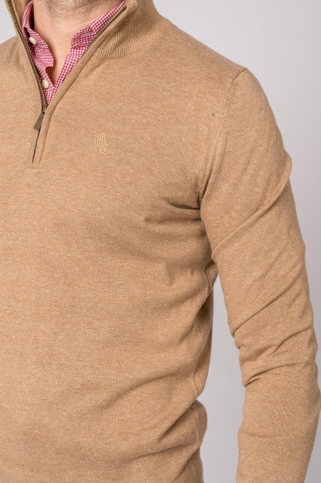 Camisola bege de malha com fecho curto e logótipo bordado no peito, usada com camisa xadrez vermelha e branca