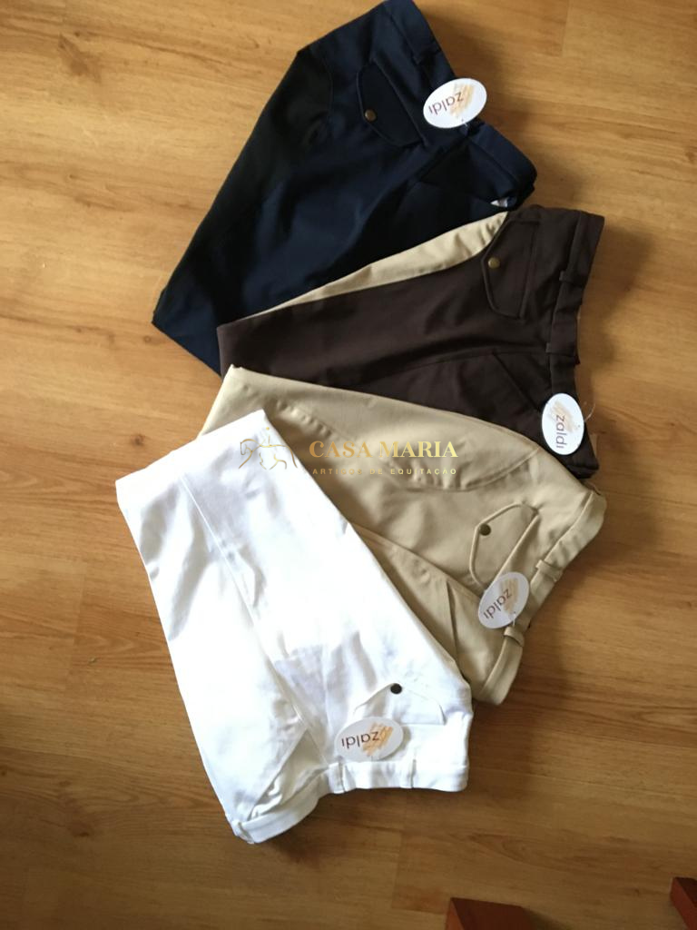 Quatro calças de criança em várias cores com etiquetas da marca Zodiac sobre chão de madeira.