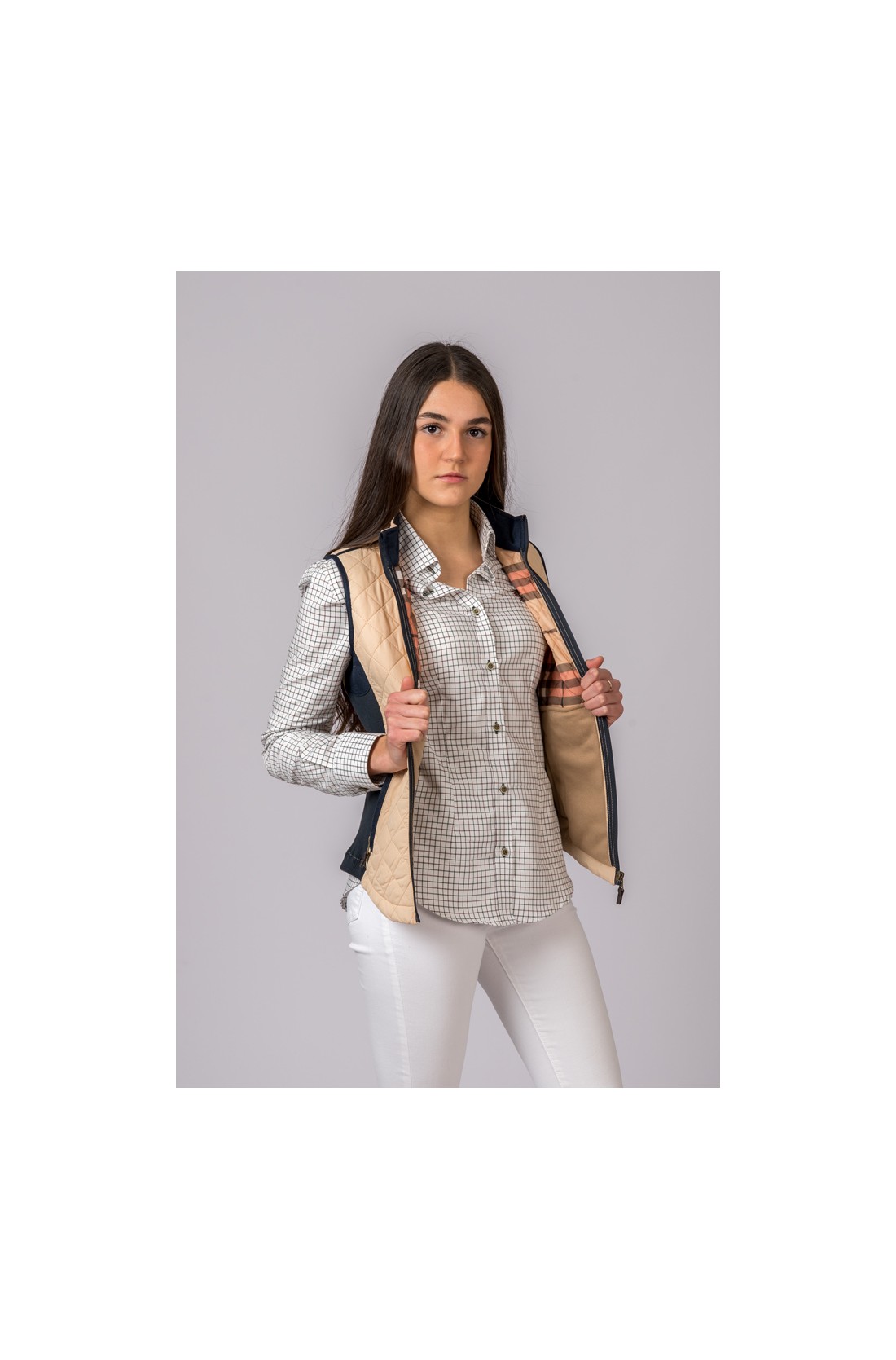 Mulher com colete bege e camisa xadrez cinza e branco