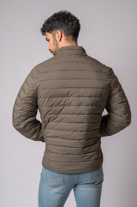 Casaco acolchoado castanho claro visto de costas com calças jeans azuis