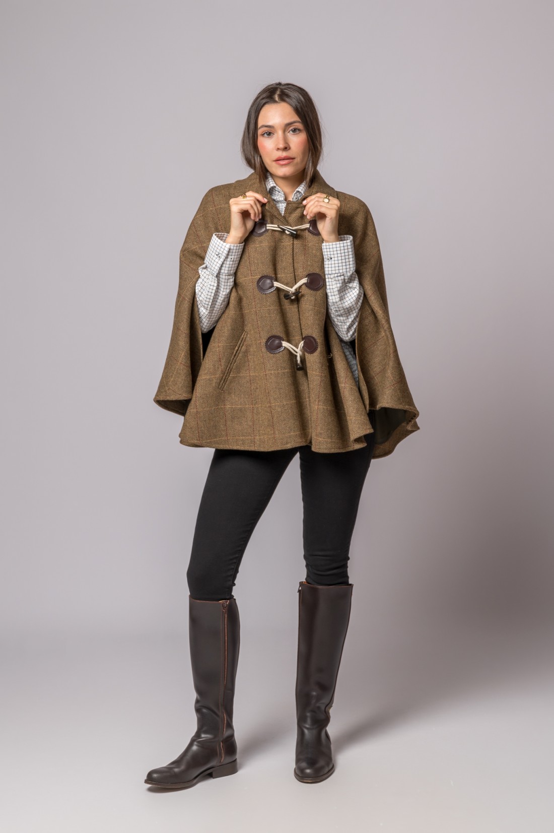 Mulher com capa castanha de padrão xadrez e botas castanhas altas