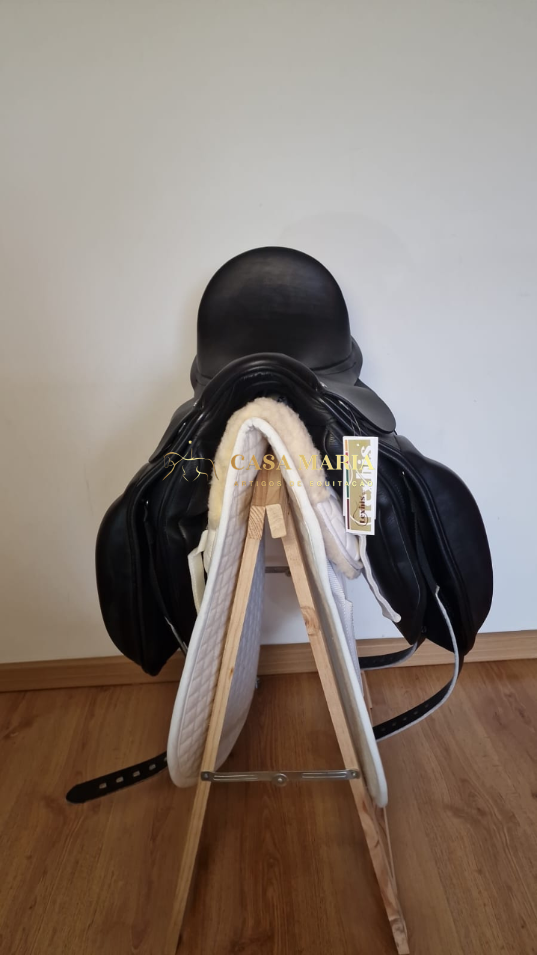 Sela de equitação preta em suporte de madeira com alforge branco