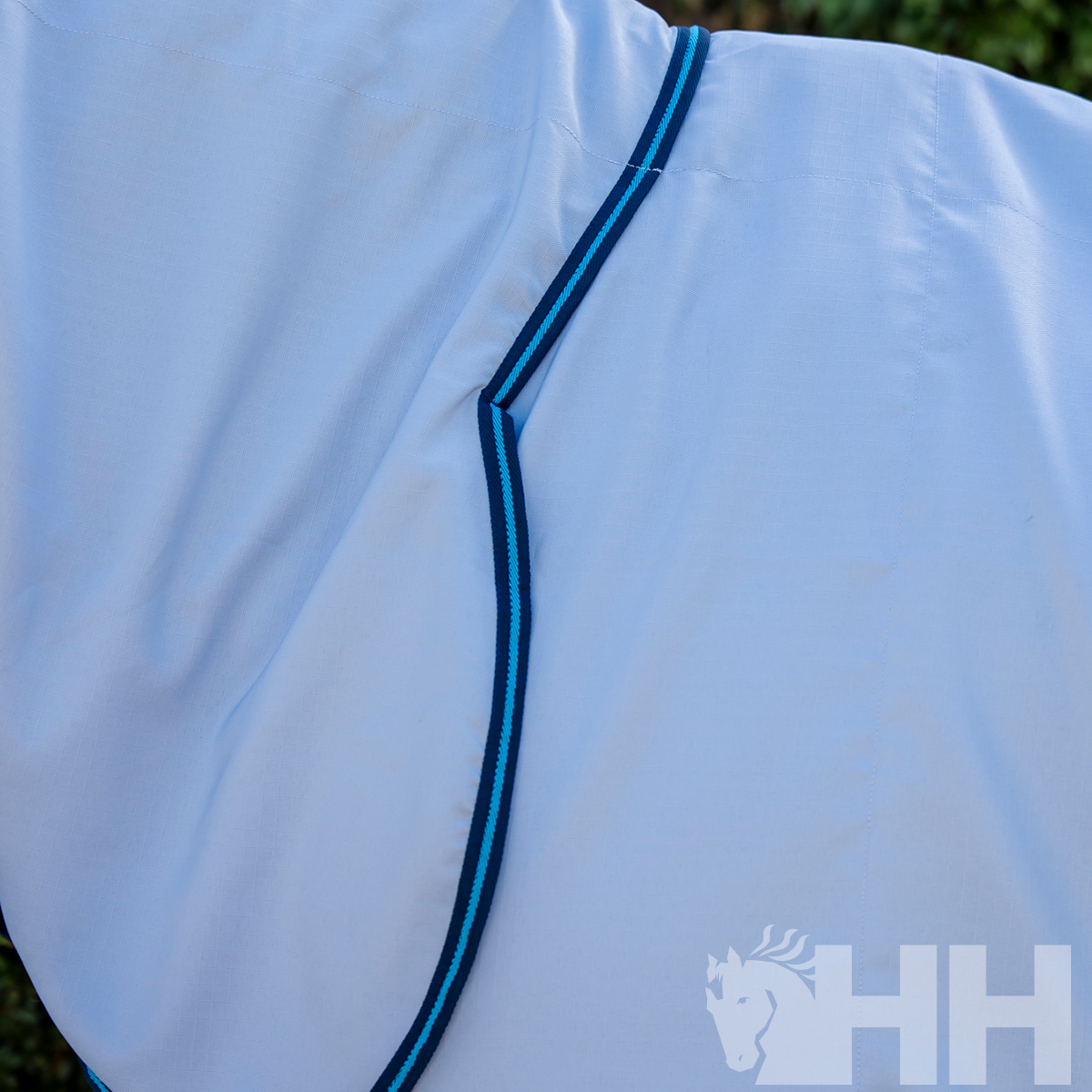 tecido branco com borda azul e logótipo HH com cabeça de cavalo