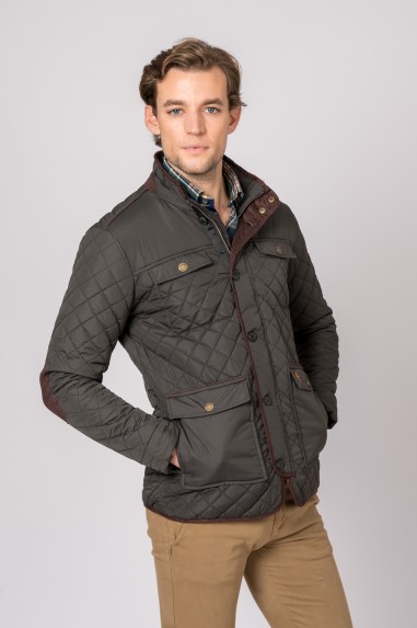 Homem a usar casaco acolchoado castanho escuro com botões dourados e bolsos, calças bege e camisa xadrez sob casaco