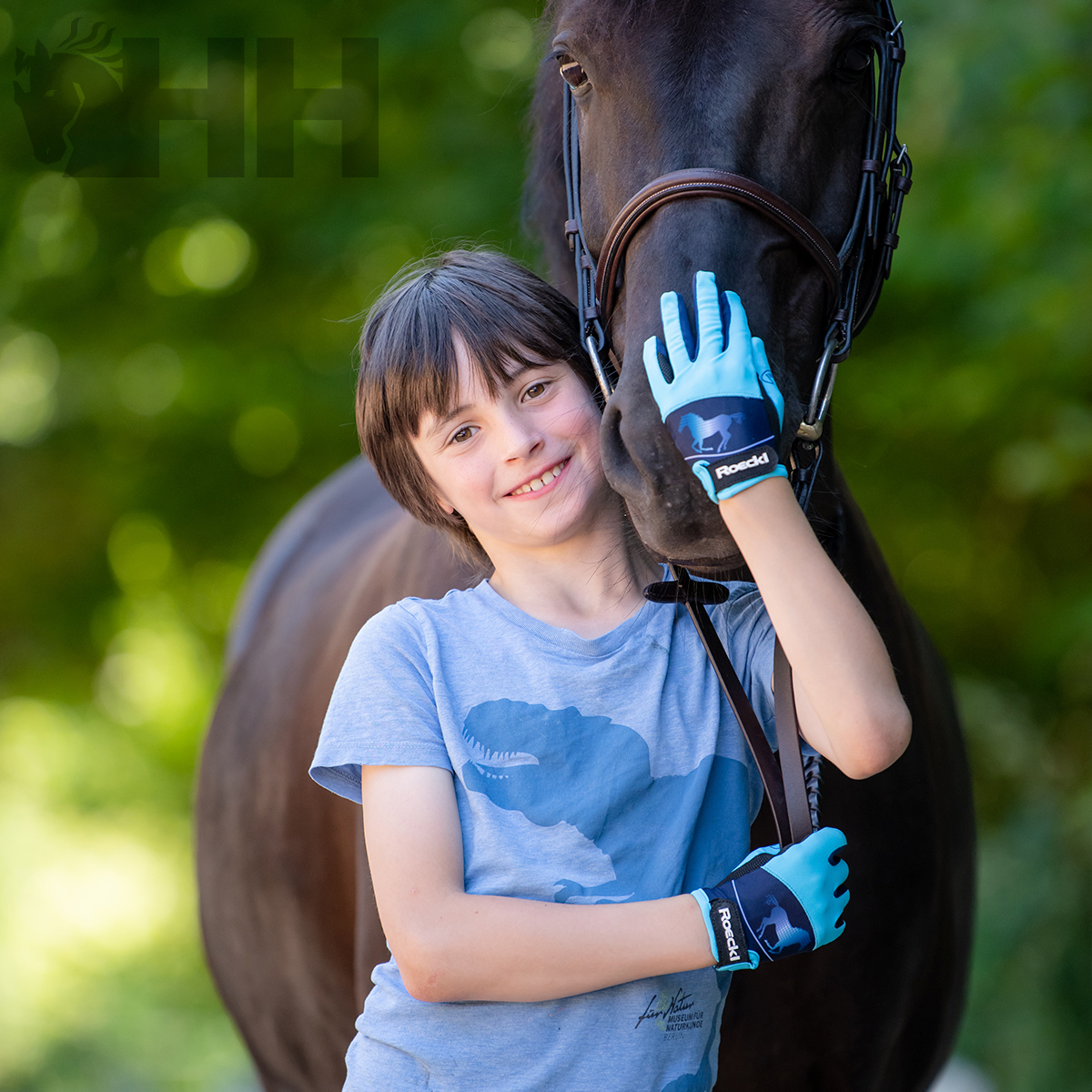 Criança com luvas azuis abraçando um cavalo castanho escuro