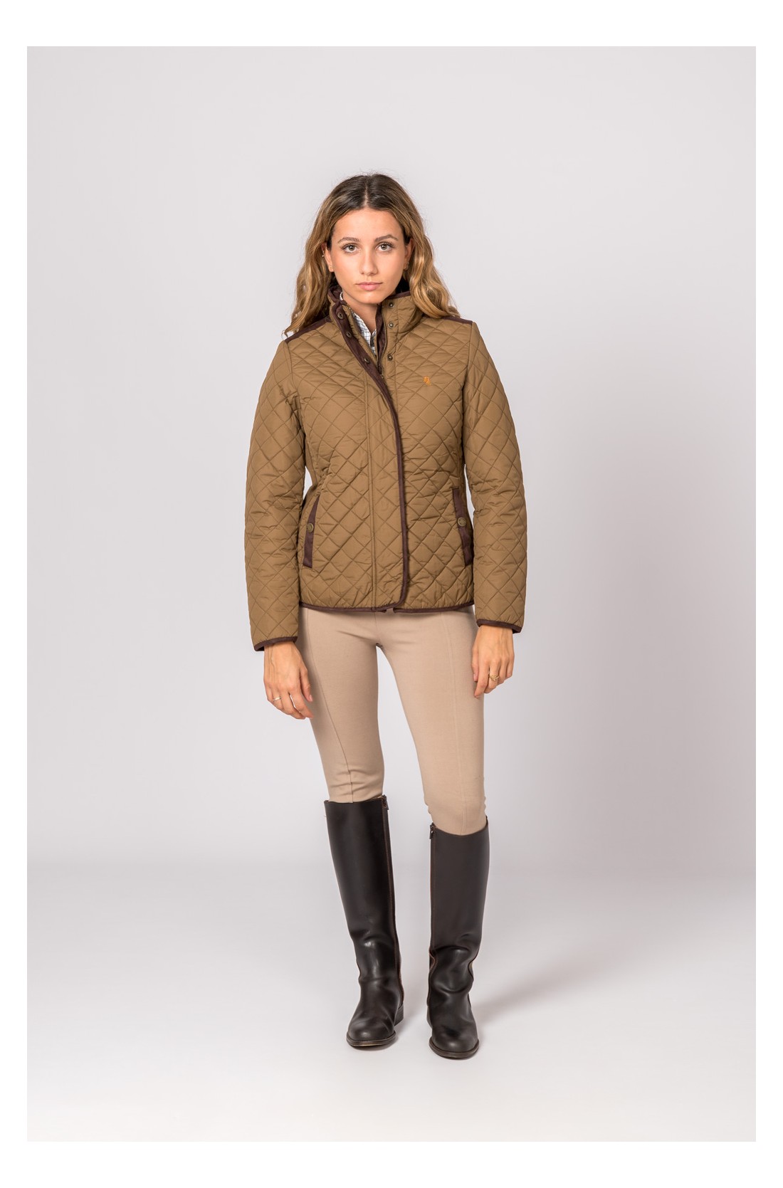 Mulher vestindo casaco acolchoado bege com zíper e calças bege, botas pretas