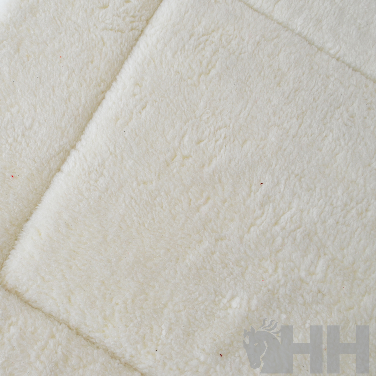 Tapete branco felpudo com padrão de quadrados e logótipo HH