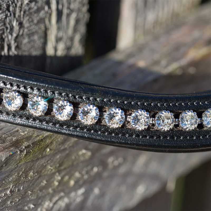 Bandolete preta em couro com cristais brilhantes colocada sobre madeira