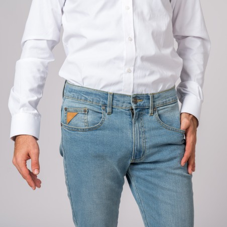 Calças de ganga azuis claras com bolso castanho e camisa branca em estúdio