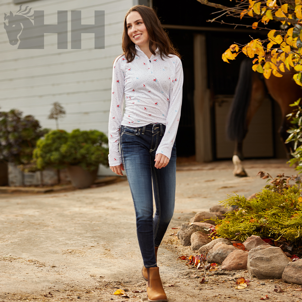 Mulher com camisa branca de manga comprida e calças de ganga numa quinta