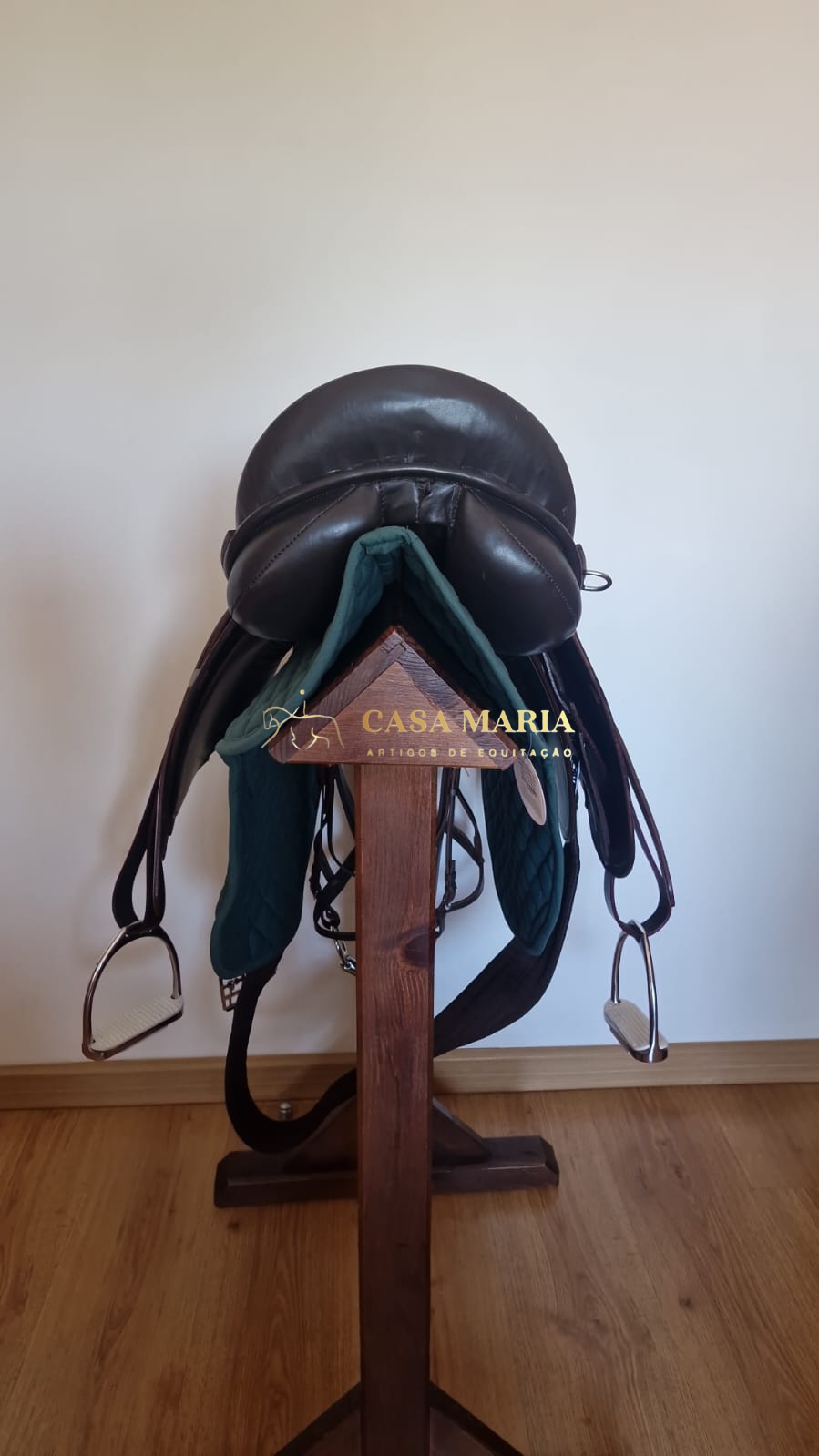 Sela de equitação preta em suporte de madeira com manta verde