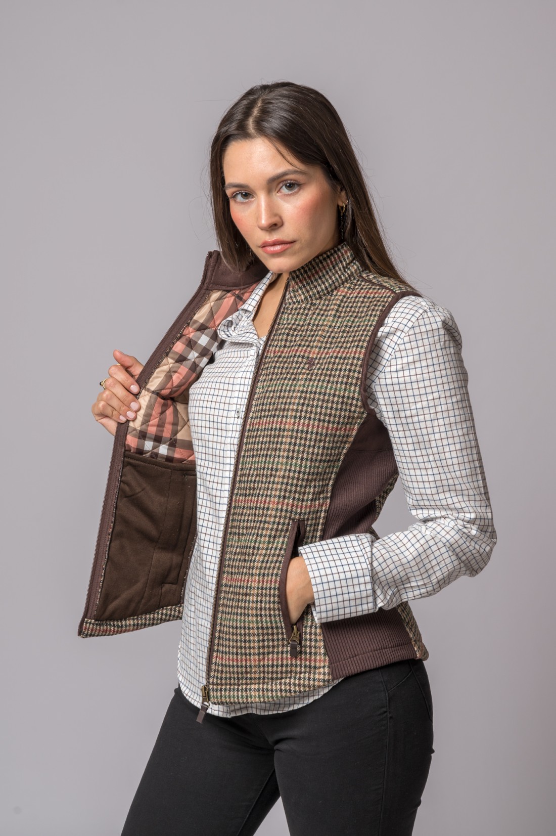 Colete feminino xadrez castanho com interior acolchoado mostrado por mulher com camisa quadriculada