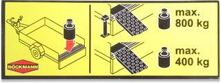 Placa amarela de instruções com textos e imagens sobre capacidades máximas de carga para atrelado.