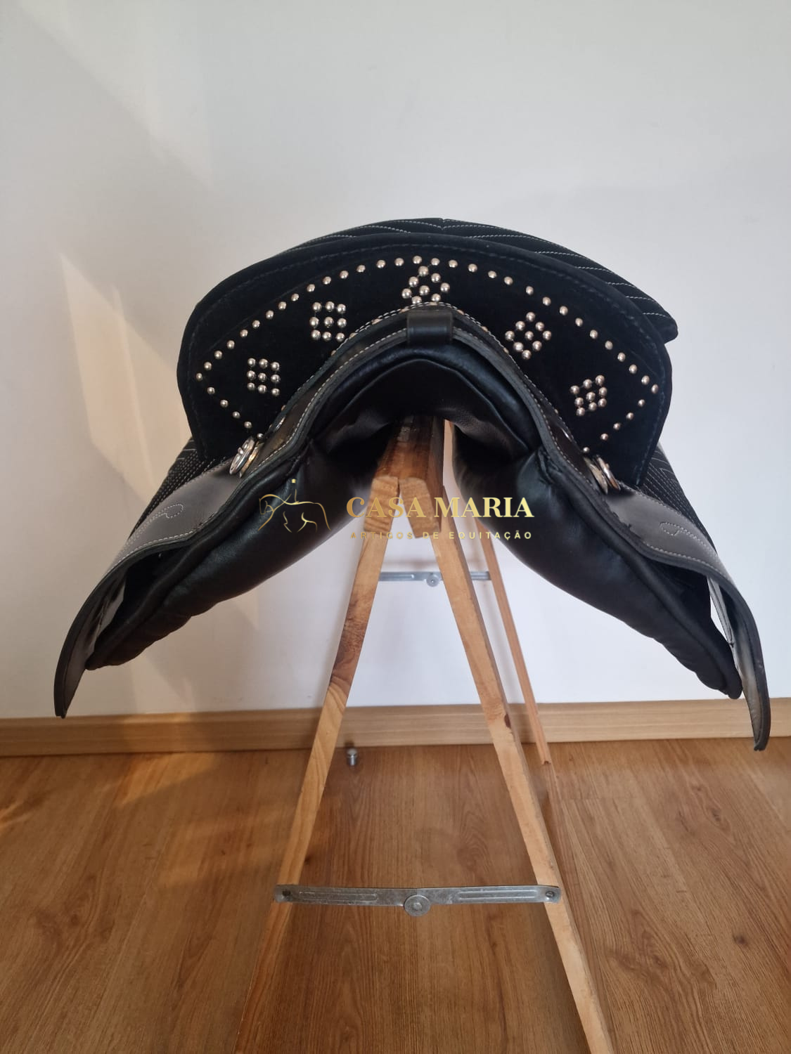 Sela de equitação preta com detalhes metálicos em madeira