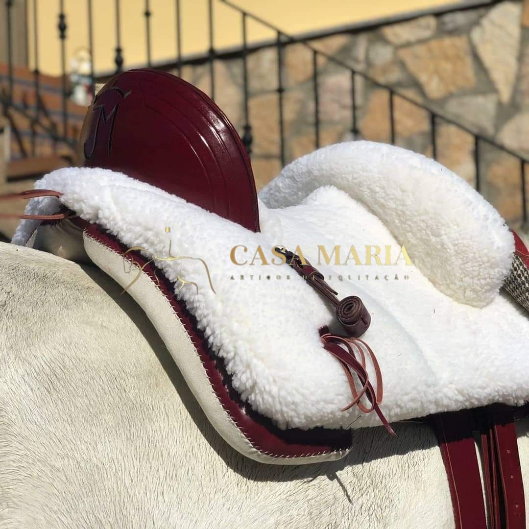 Sela de equitação vermelha com forro branco de lã em cavalo claro