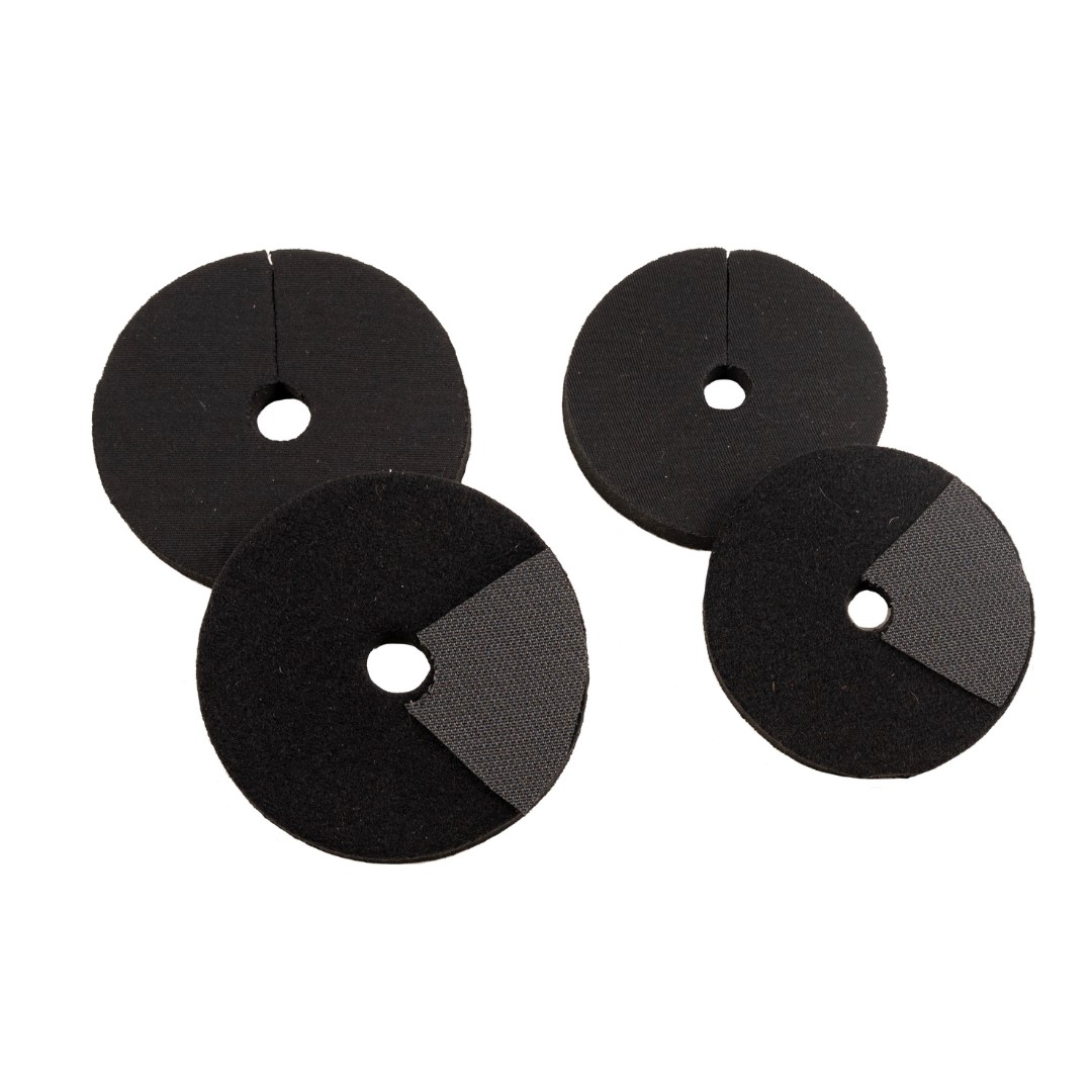 Quatro proteções redondas de espuma preta com orifício central e recorte em material distinto