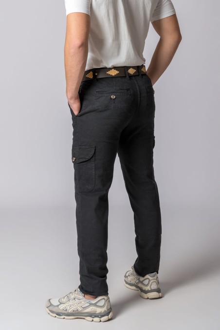 Pessoa de costas com calças cargo pretas, cinto castanho, t-shirt branca e ténis cinzentos.