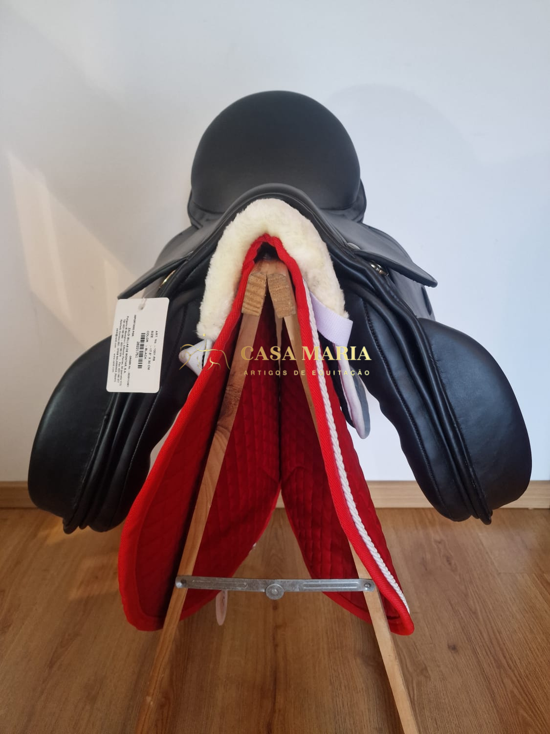 Sela equestre preta de couro sobre suporte com manta vermelha