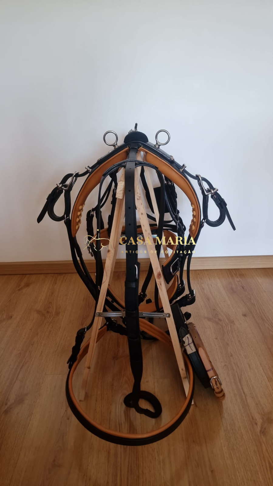 Arreio de equitação preto e bege em suporte de madeira