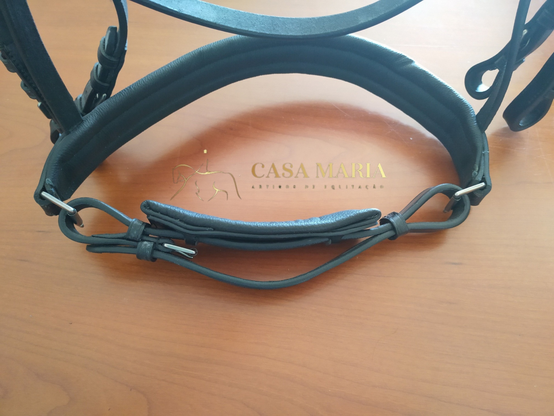 Estribo de montaria em couro preto sobre placa em couro castanho com texto CASA MARIA