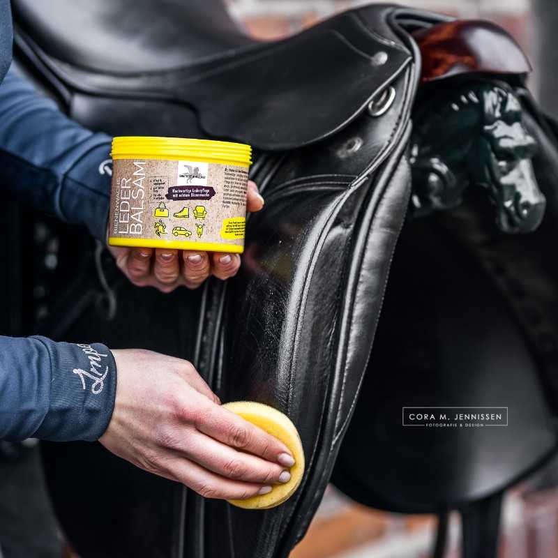 Aplicação de bálsamo para couro em sela de cavalo preta com esponja amarela