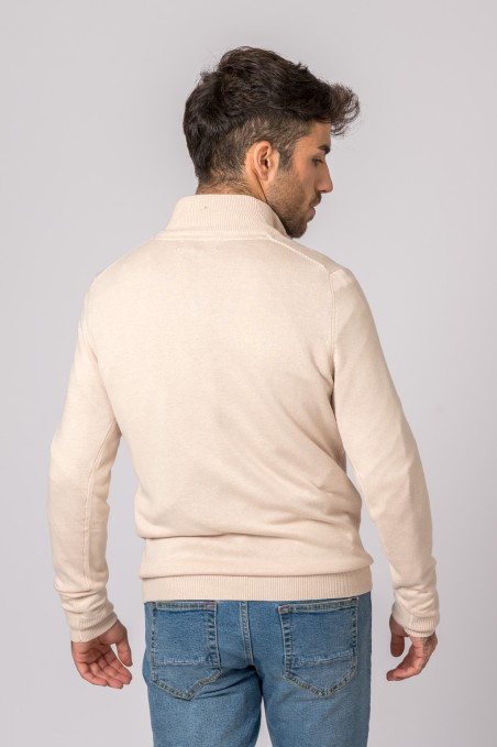 Homem de costas a vestir camisola bege de malha com gola alta e calças de ganga azuis