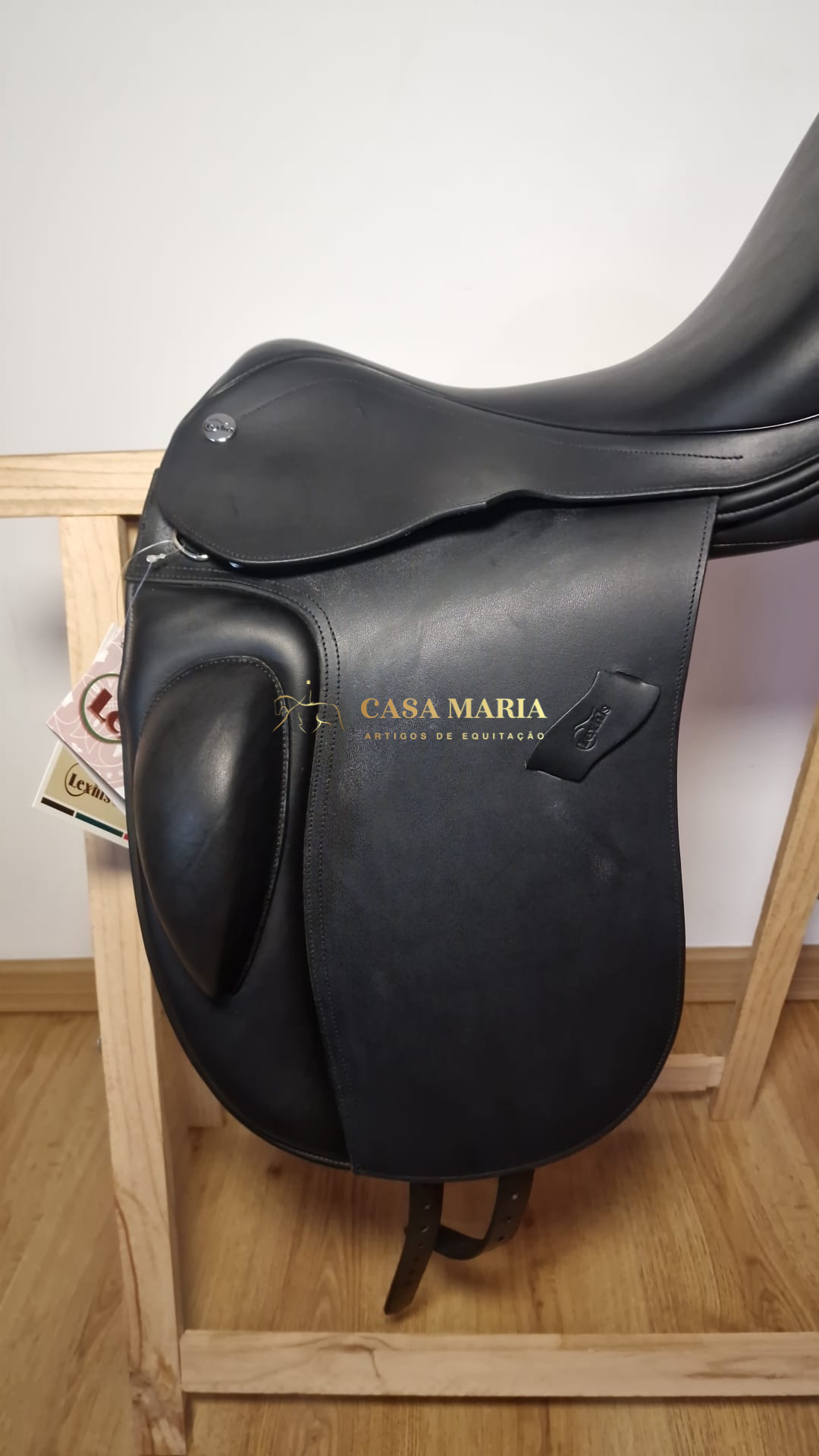 Sela de equitação preta em pele sobre suporte de madeira