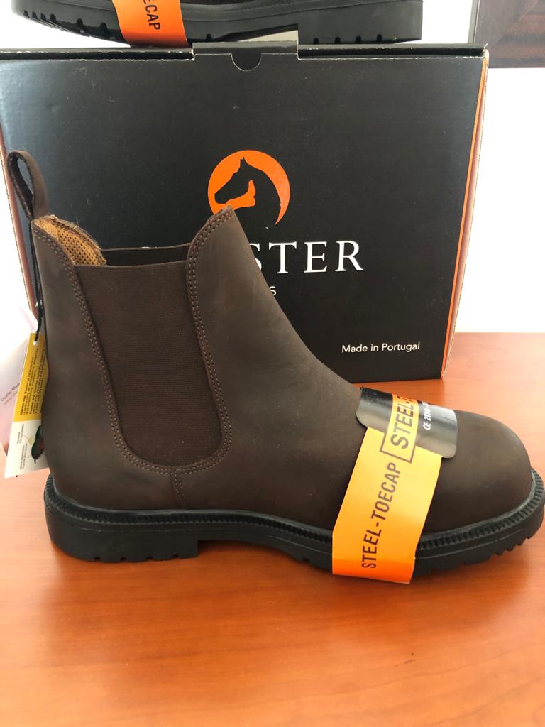 Bota de couro castanha escura com sola preta e etiqueta amarela 'STEEL TOE CAP' à frente de caixa preta