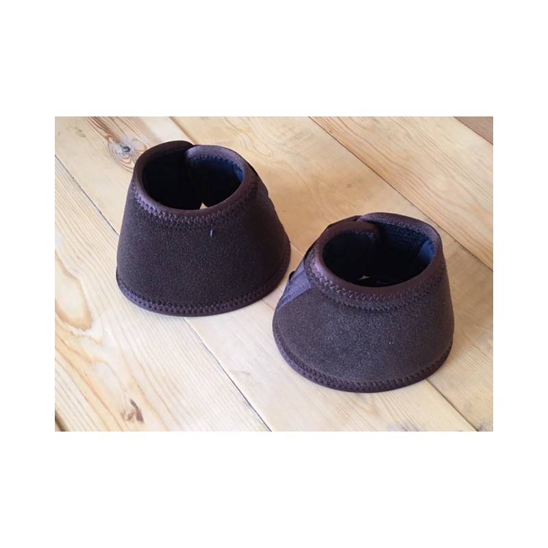 Botins ou coberturas de patas para cavalo castanhos sobre chão de madeira