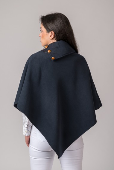 Capa azul escura com gola alta e botões castanhos usada por mulher de costas.