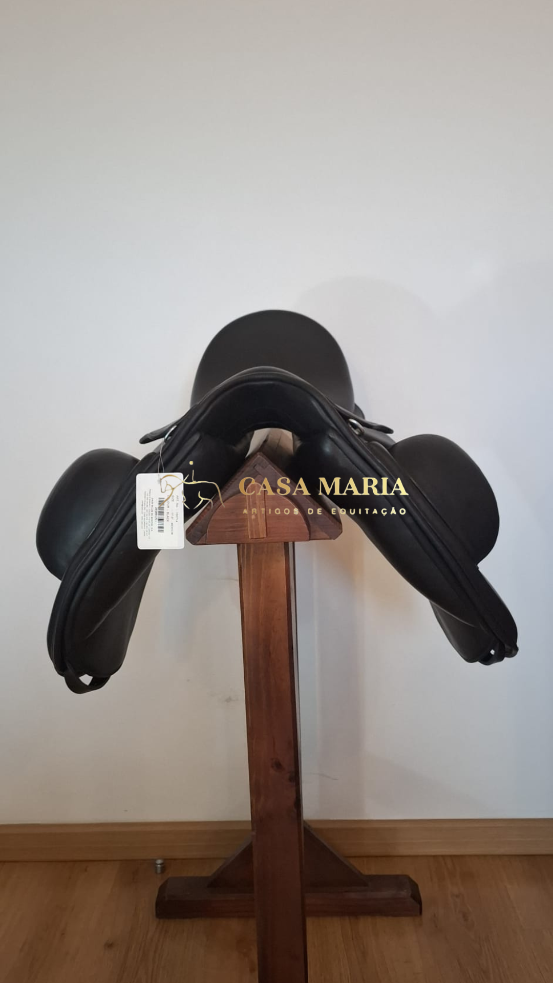 Sela de equitação preta em suporte de madeira com etiqueta