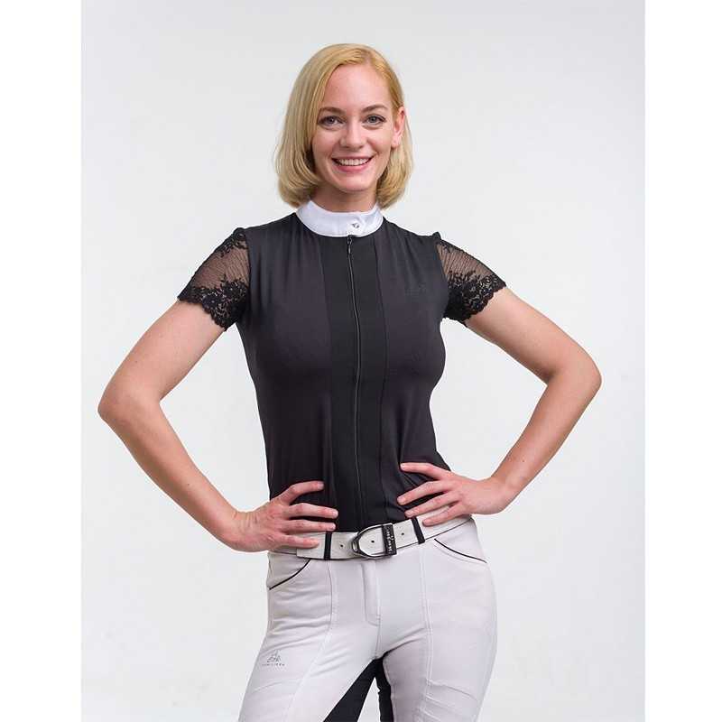 Mulher com blusa preta com gola branca e mangas de renda, calças claras e cinto branco sobre fundo branco