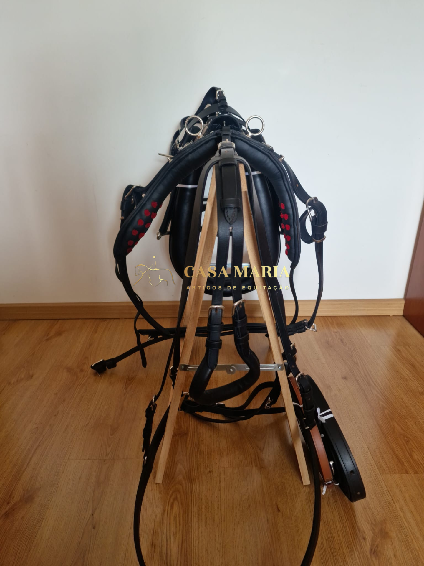 Sela de equitação em couro preto num suporte de madeira