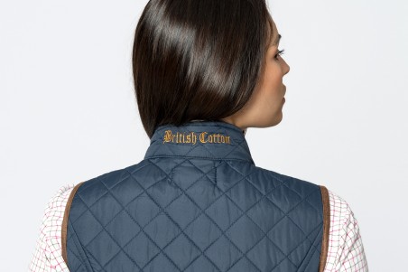 Colete azul acolchoado com bordas castanhas e inscrição British Cotton na gola