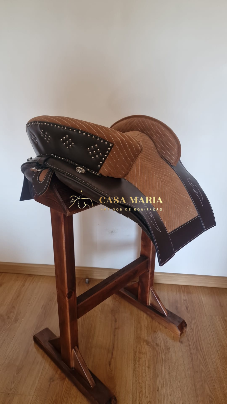 Sela de montar castanha com detalhes em couro escuro sobre suporte de madeira
