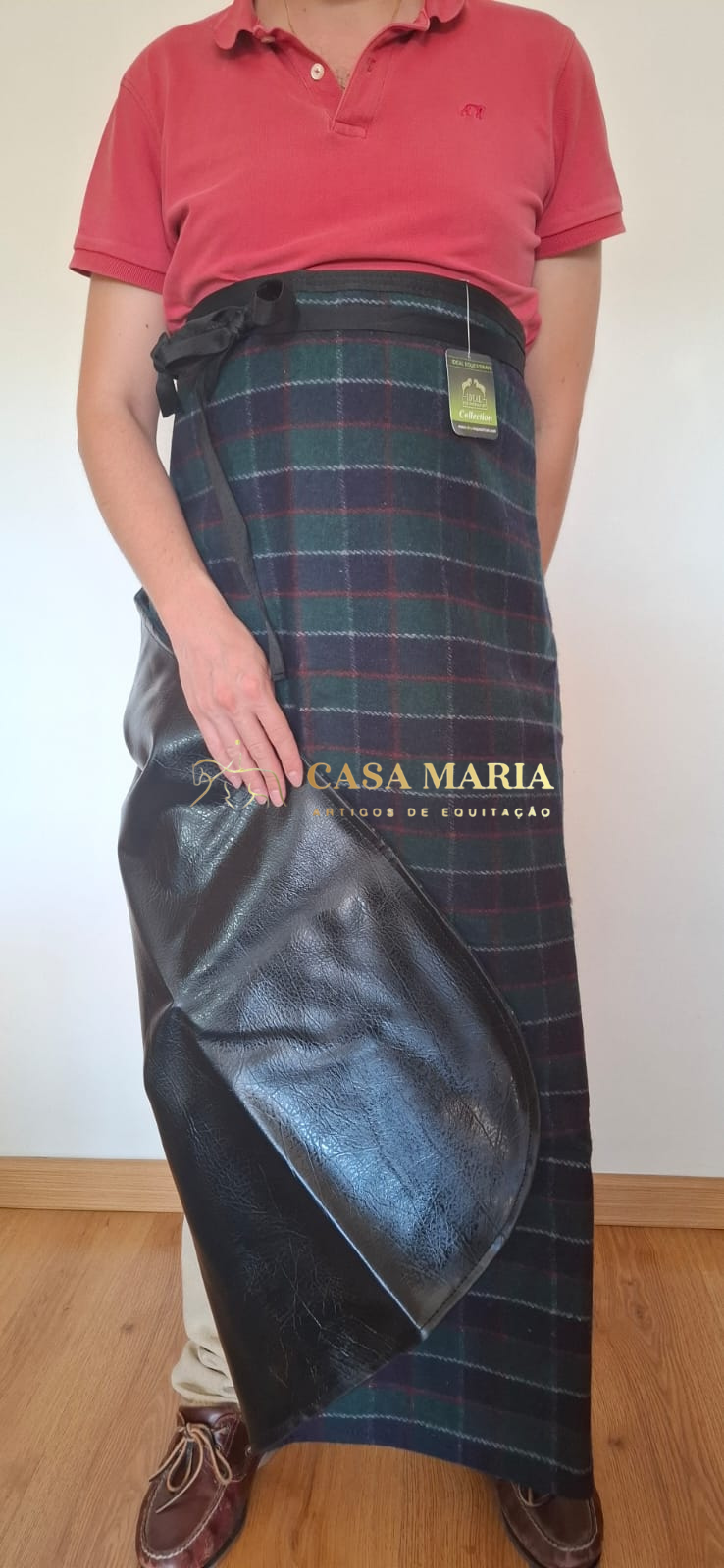 Pessoa vestindo camiseiro rosa e saiote tartan com partes em pele preta e etiqueta pendurada.