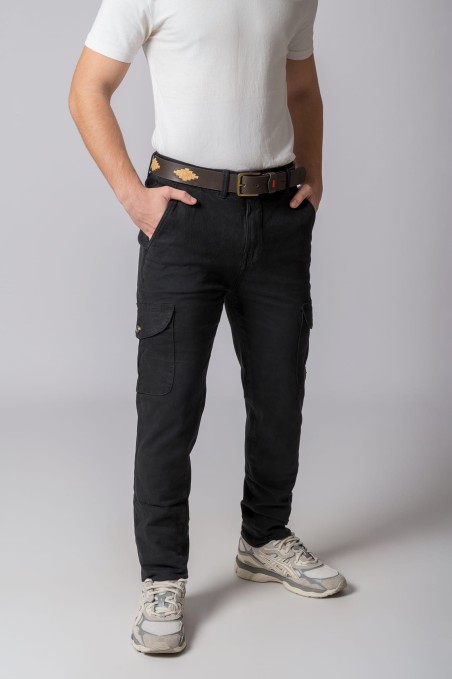 Modelo com calças cargo pretas, cinto castanho, t-shirt branca e ténis desportivos em fundo cinza