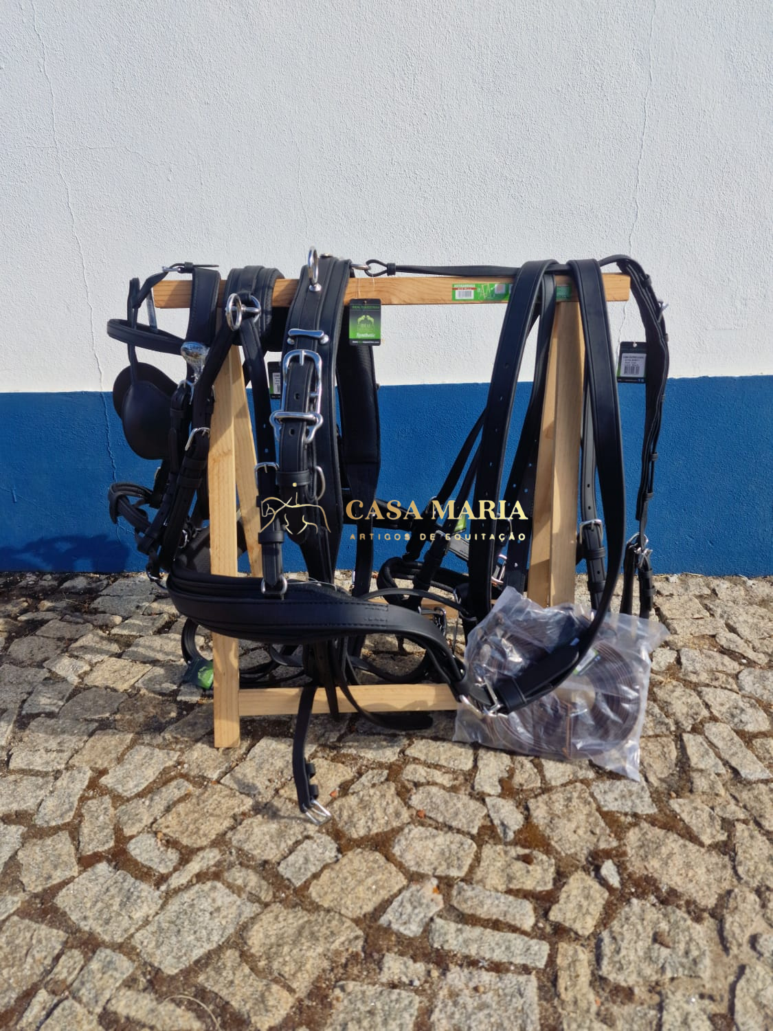 Equipamento de equitação preto pendurado em suporte de madeira em piso de calçada comerciado