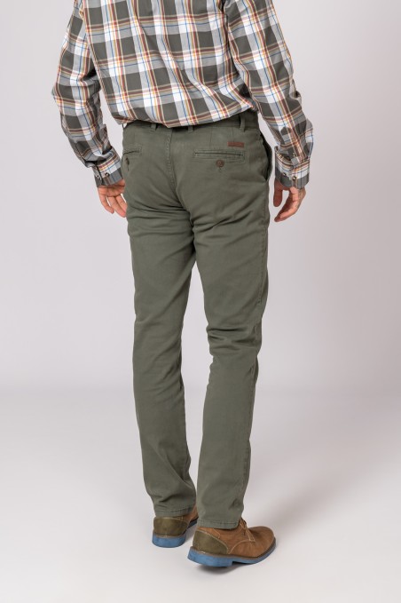 Homem vestido com calças verdes e camisa xadrez em fundo cinzento