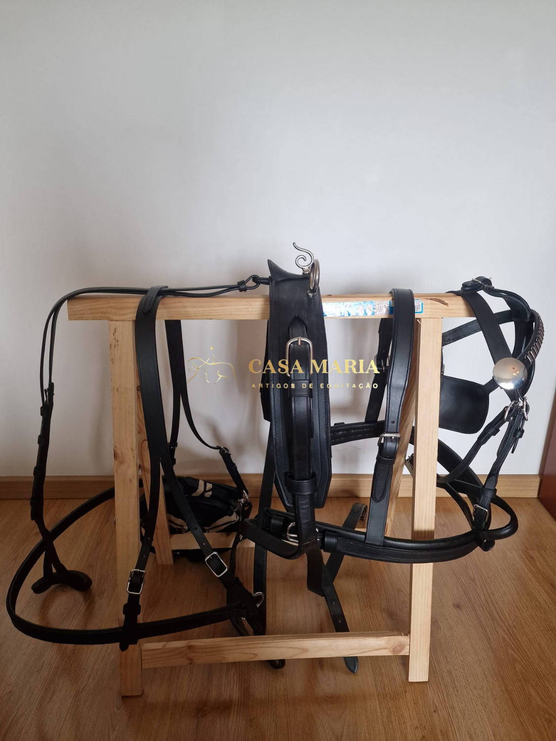 Bridão preto de equitação pendurado em estrutura de madeira