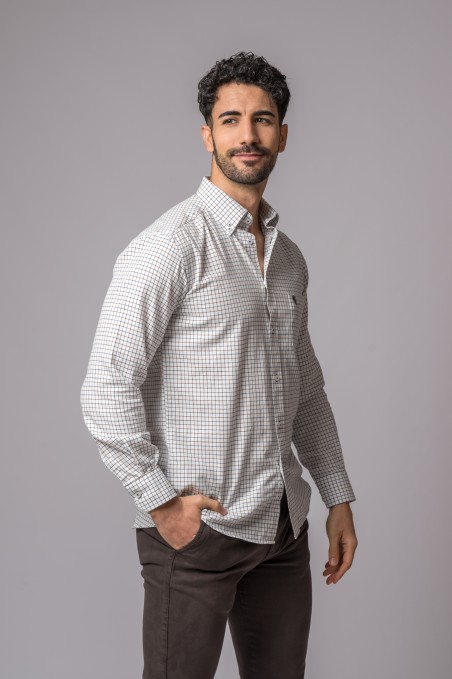 Homem com camisa xadrez cinza e branca de manga comprida e calças castanhas