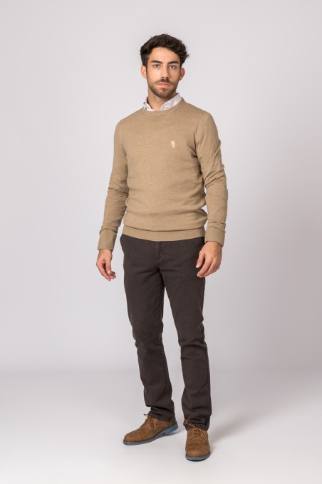 Homem com camisola bege, calças castanhas e sapatos castanhos em fundo branco